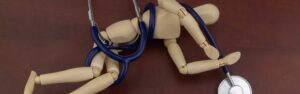 Stick figure wrapped in stethoscope laying down on ground after medical malpractice